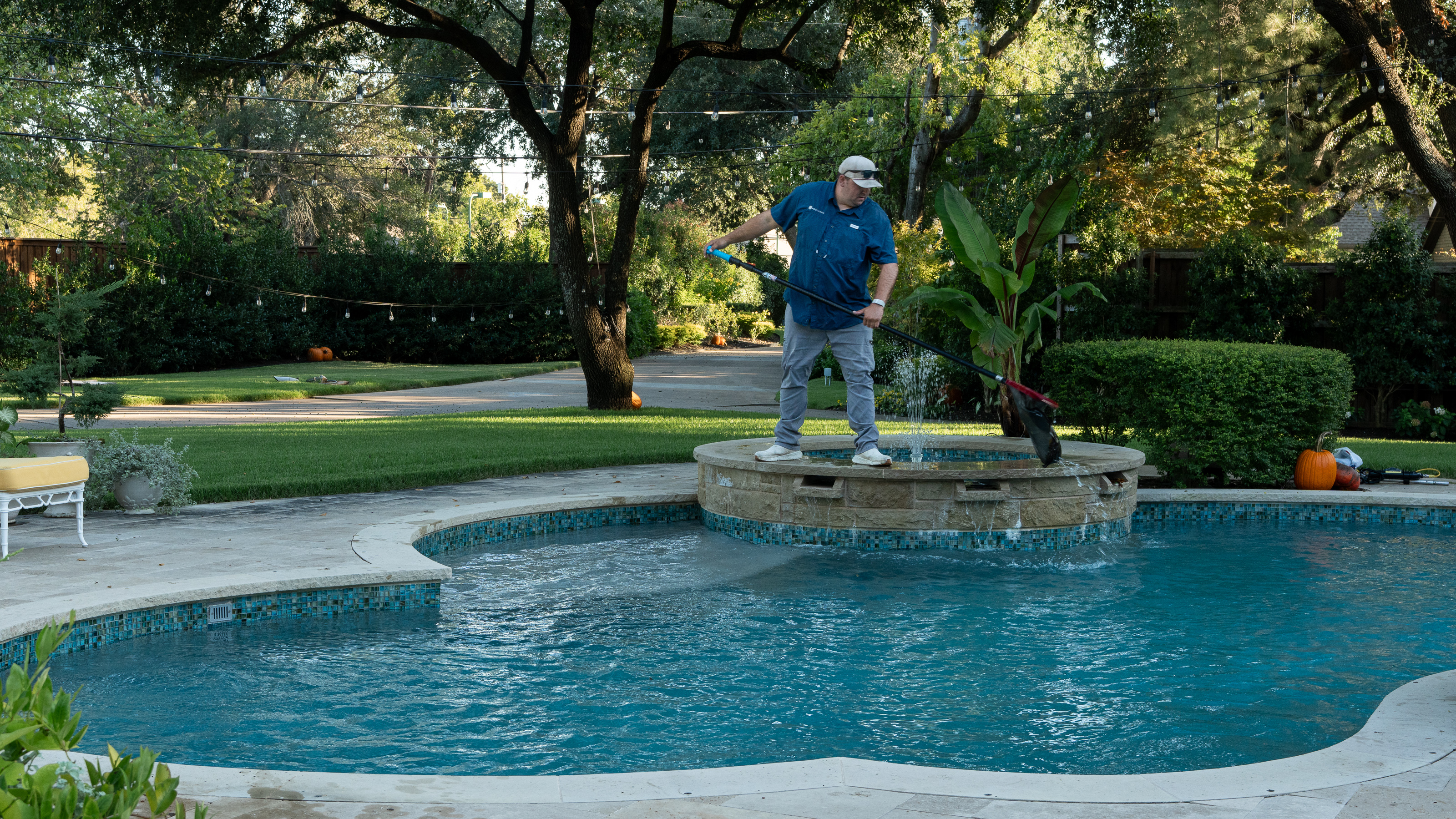 A PoolVana technician cleaning an in-ground pool